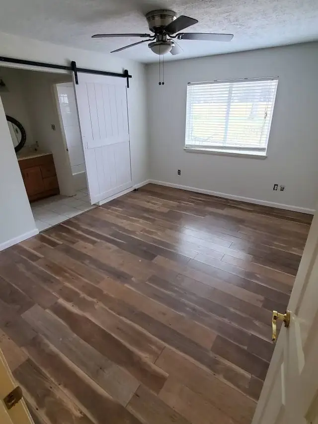 An emptied commercial interior with a barn door and clean wood floor, ready to hand back to the owner