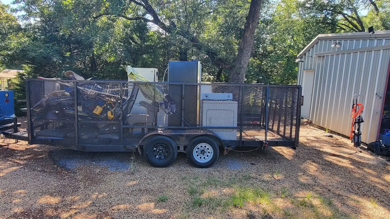 A loaded HCC trailer beside a commercial metal building during a cleanout in Henderson County