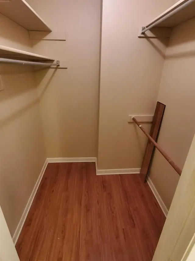 The same walk-in closet stripped to bare rails and clean wood floor