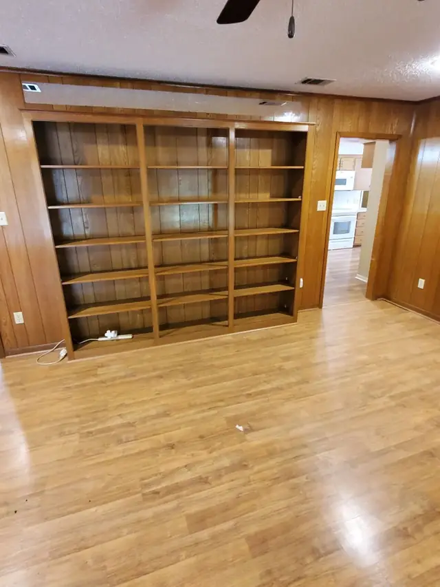 The same wall of built-in bookshelves completely emptied and the floor cleared after HCC's estate cleanout