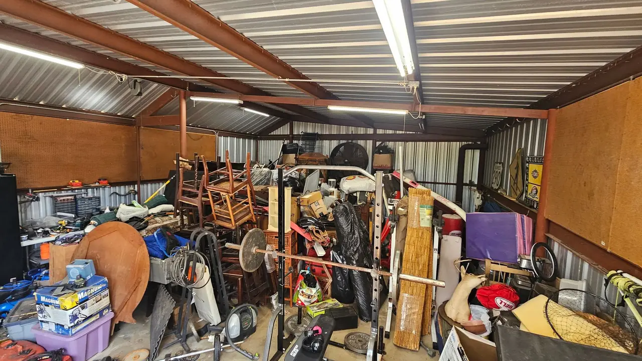 A metal shop building in Henderson County packed floor to ceiling with tools, exercise equipment, lumber and stored furniture