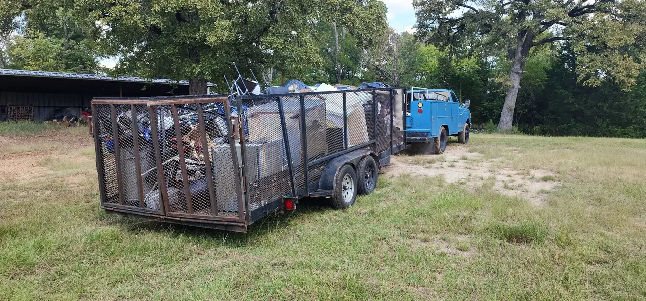 Two HCC trailers loaded with cleared household junk and appliances on a job site in Henderson County, Texas
