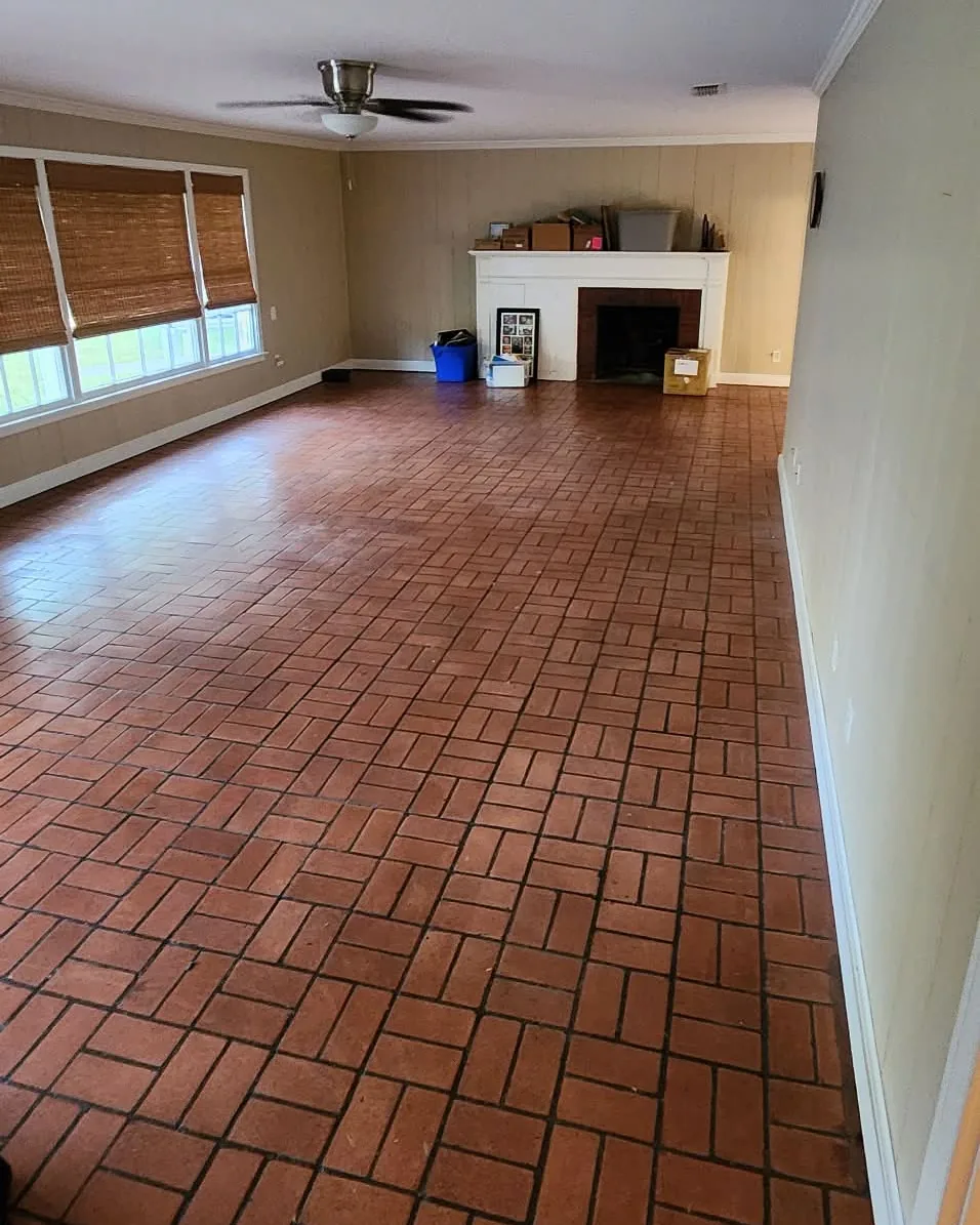 The living room after removal, with the brick floor cleared and a few belongings remaining by the fireplace